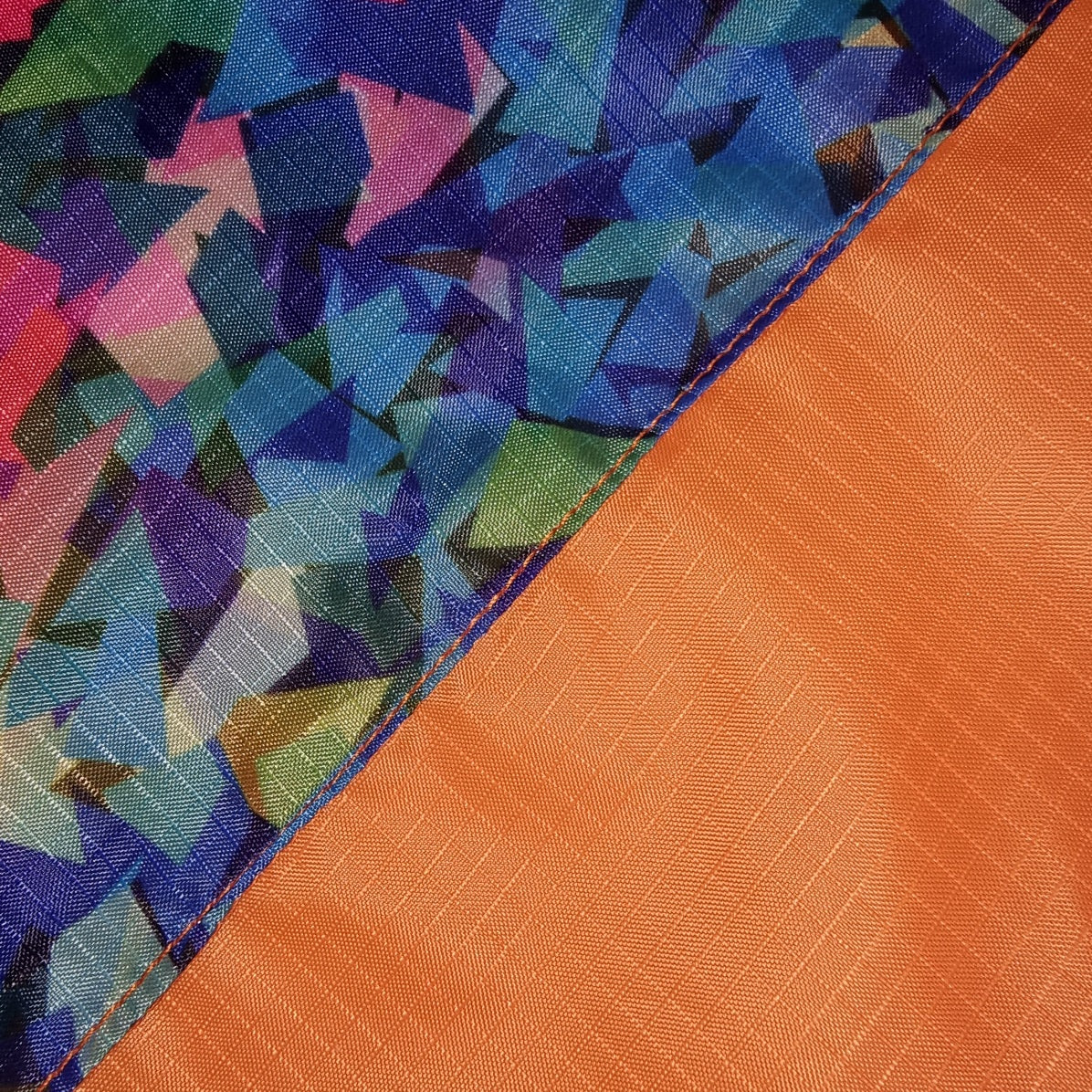 Close-up of colorful geometric patterned fabric and orange textured fabric of the Fusion Flag