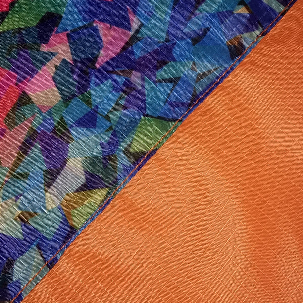 Close-up of colorful geometric patterned fabric and orange textured fabric of the Fusion Flag