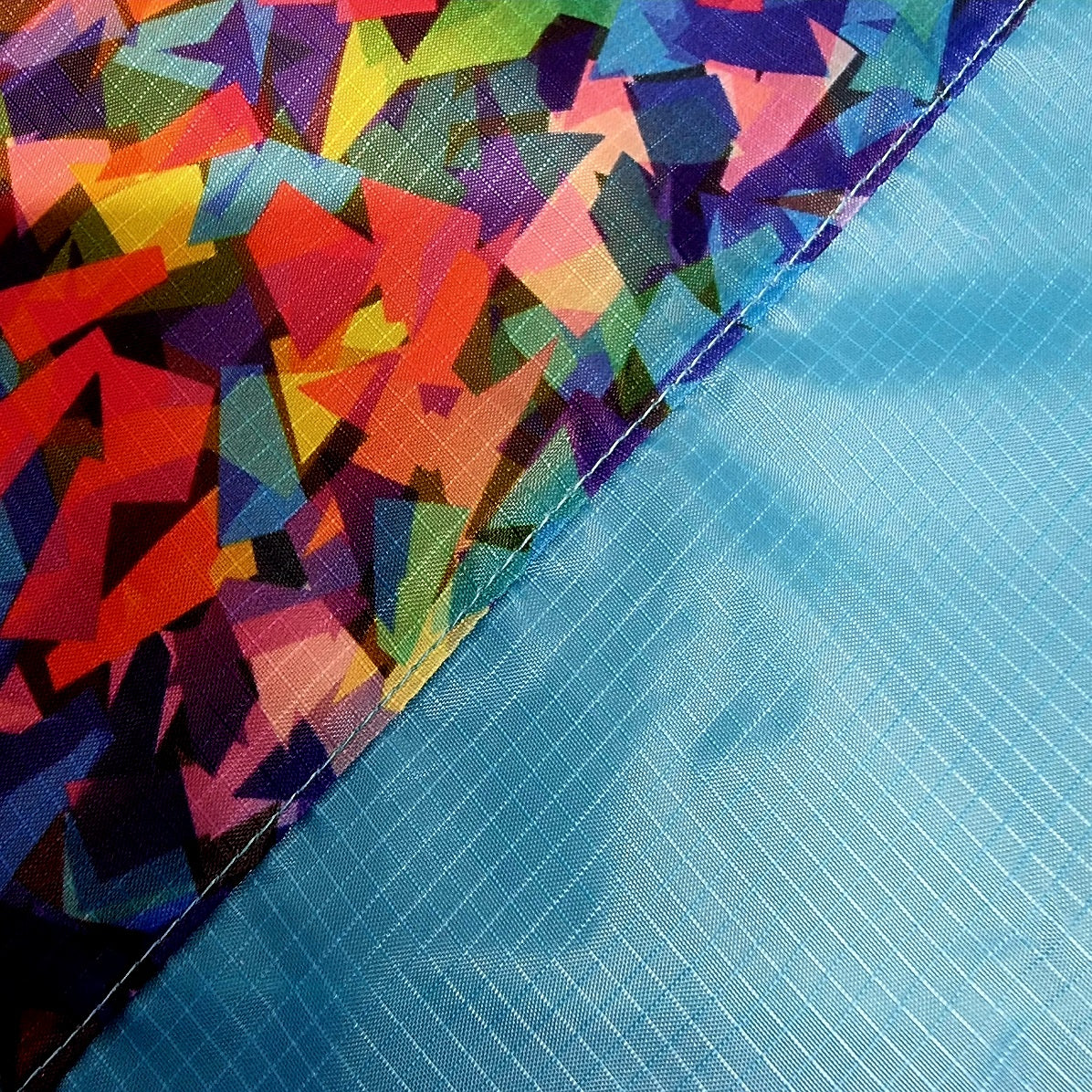 Colorful geometric-patterned fabric next to a blue textured surface flag swatch