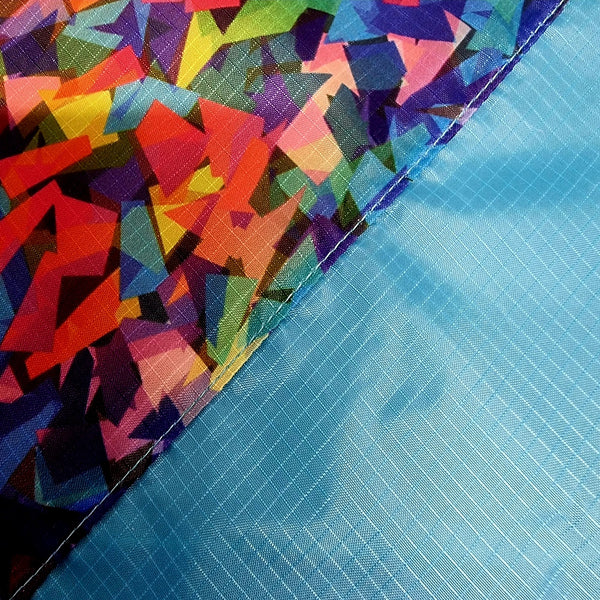 Colorful geometric-patterned fabric next to a blue textured surface flag swatch