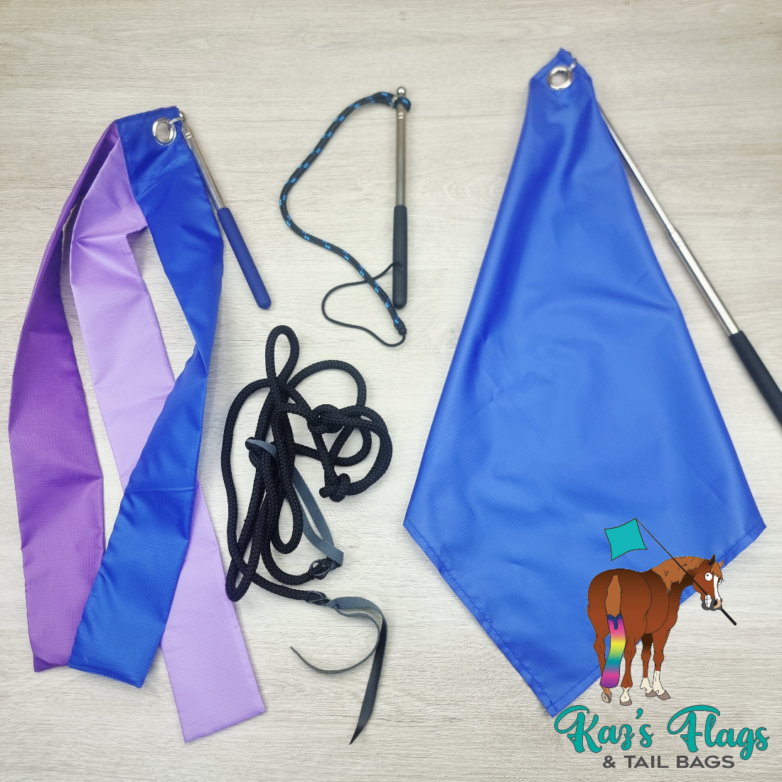 A set of equestrian tail flags and reins laid out on a light wood background, including a blue and purple ribbon flag, a blue flag with a silver pole, black reins, and a blue-and-black lead. The 'Kar's Flags & Tail Bags' logo is visible in the bottom right corner.