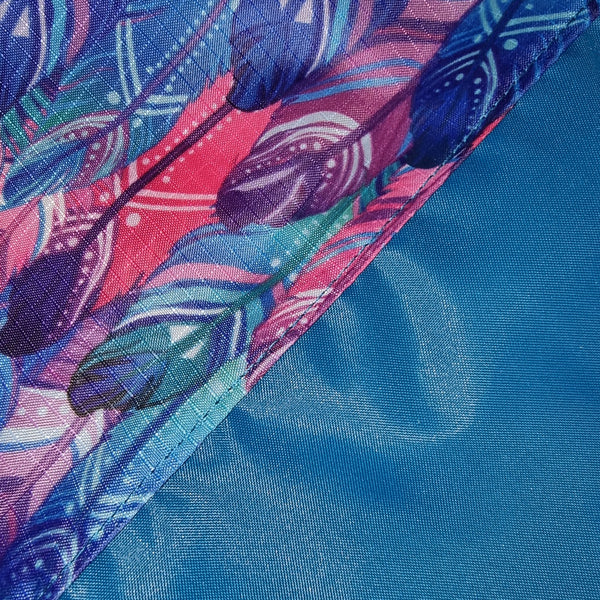 Close-up of a fabric with colorful feather pattern on a blue background