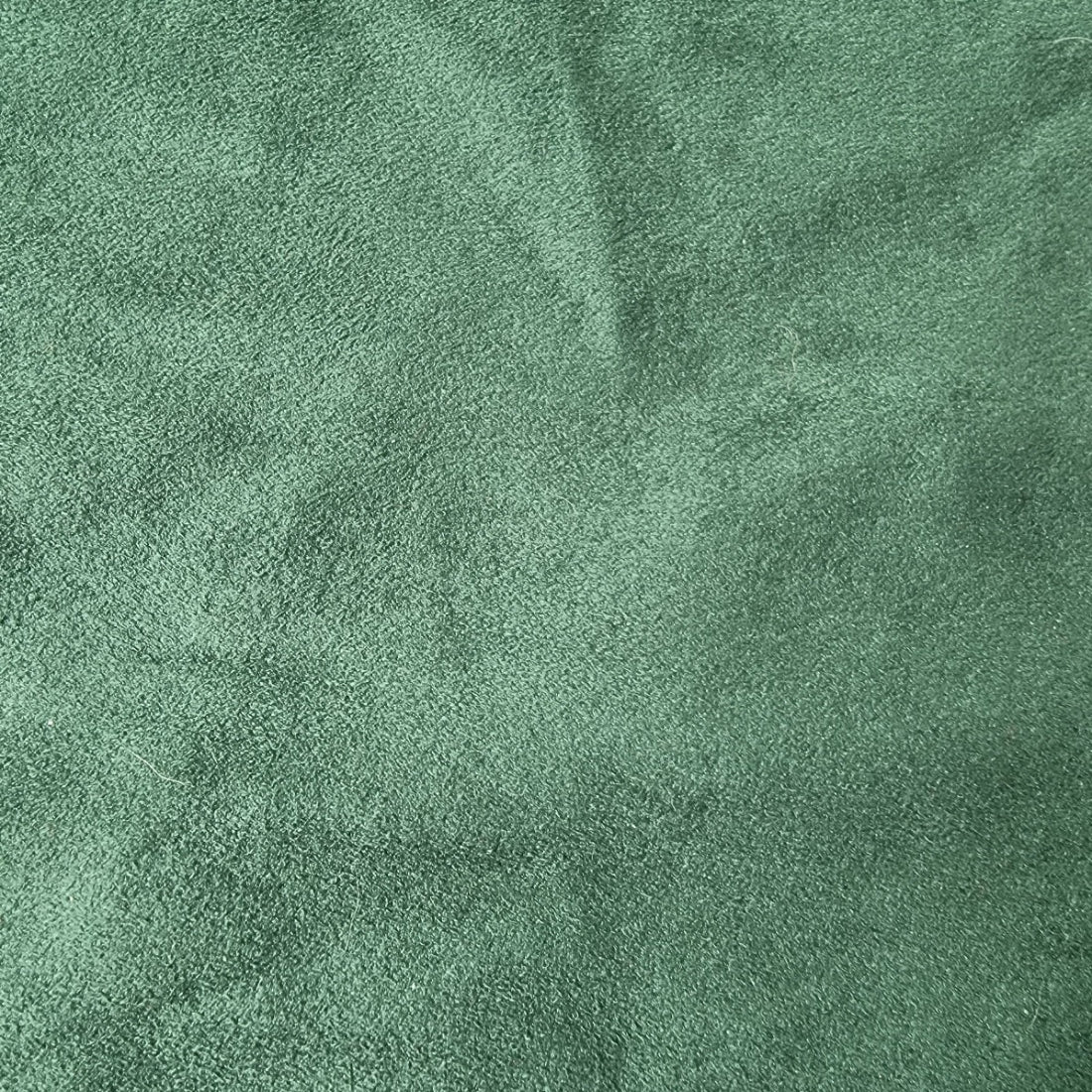 A close-up of a textured green fabric surface with a soft, slightly mottled finish.