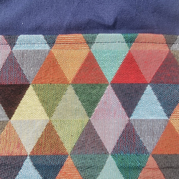 A close-up of a woven textile featuring a geometric diamond pattern in multiple colors including orange, green, red, blue, pink, and gray, with a solid navy blue section at the top.