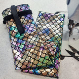 Multicolored fish-scale patterned tail bag with a black strap on a light gray surface.