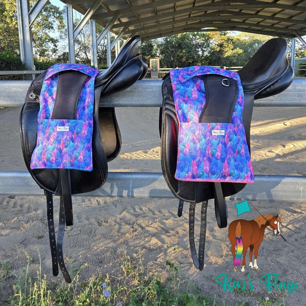 Two horse saddles with colorful stirrup covers on a metal surface.