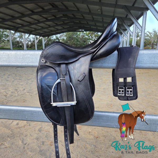 Black leather saddle with a matching black leather pad on a metal railing, with 'Kaz's Flags & Tail Bags' logo in the corner.