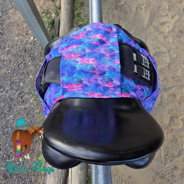 Colourful Stirrup and Girth Holder sitting over a saddle in an outdoor equestrian setting