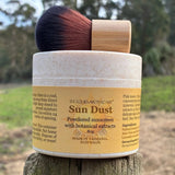 Sun Dust powdered sunscreen with botanical extracts on a wooden surface outdoors