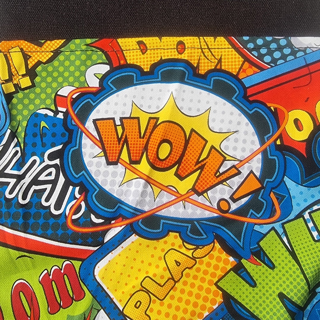 A close-up of a vibrant comic book style print featuring a central 'WOW!' speech bubble with yellow, orange, blue, and white halftone patterns, surrounded by bold comic text and colorful panels.